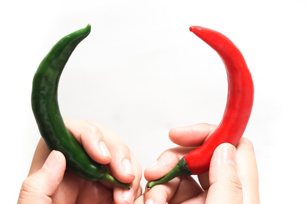 Ręka trzymająca czerwoną i zieloną gorącą paprykę chili izolowaną na białym tle