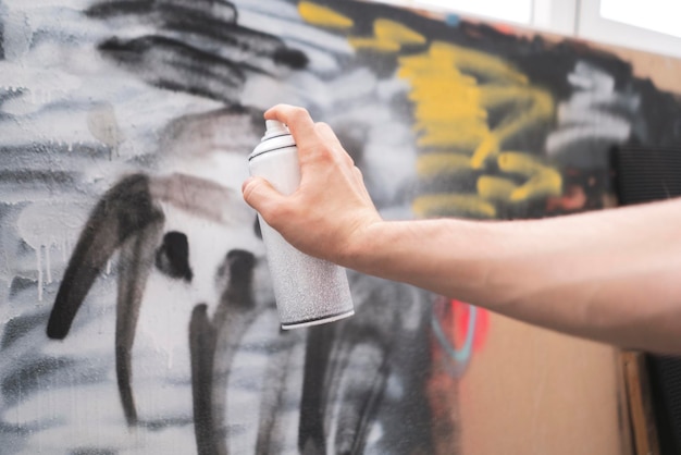 Ręka trzymająca farbę w sprayu może artysta wykonujący graffiti na ścianie