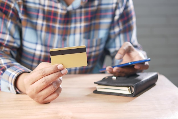 Ręka trzymająca kartę kredytową i smartfon robi zakupy online