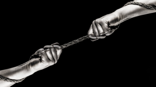 Zdjęcie ręka trzymająca linę, lina wspinaczkowa, siła i determinacja. dwie ręce, pomocna dłoń, ramię, przyjaźń. ratunek, pomoc, pomoc, gest lub ręce. konflikt, przeciąganie liny. lina, sznur. czarny i biały.