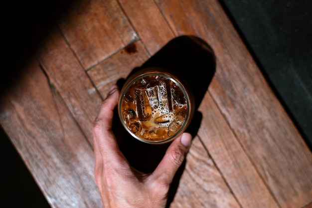 Zdjęcie ręka trzymająca mrożoną kawę na wynos na czarnym stole