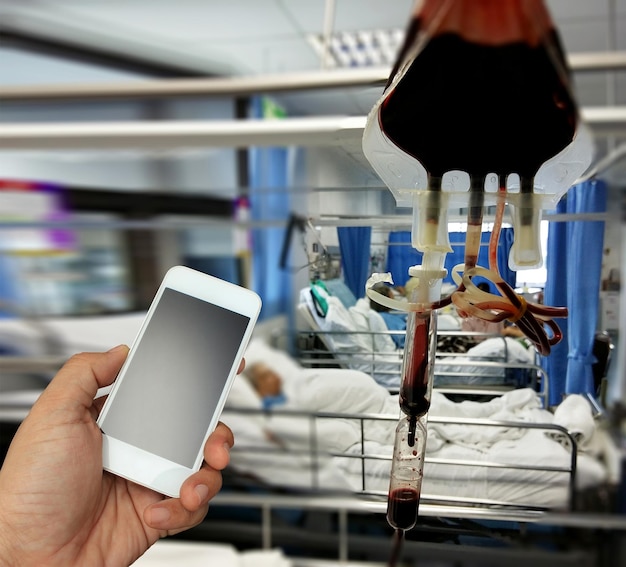 Ręka trzymająca smartfon w sali szpitalnej