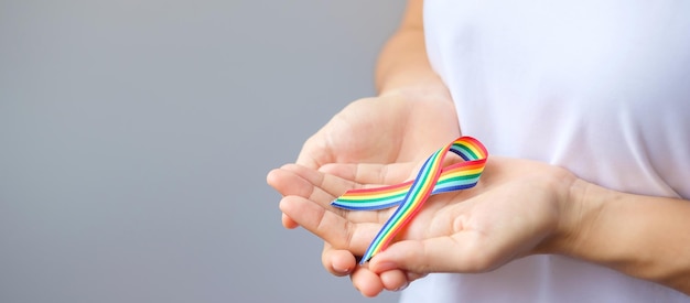 Ręka trzymająca wstążkę LGBTQ Rainbow dla wsparcia lesbijek gejów biseksualnych osób transpłciowych i społeczności queer oraz koncepcji miesiąca dumy