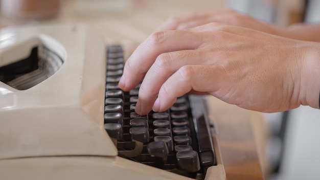 Ręka używa Roczników maszyna do pisania na drewnianym stole.