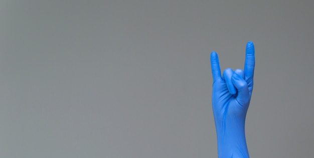 Ręka w lateksowej rękawicy chirurgicznej, pokazująca gest fanów ciężkiej mety. Copyspace