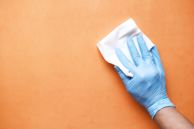 Ręka w niebieskie gumowe rękawiczki do czyszczenia stołu z ręcznikiem.