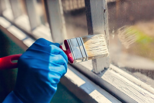 Zdjęcie ręka w rękawiczce maluje ramę okienną naprawa w domu usługi malarza