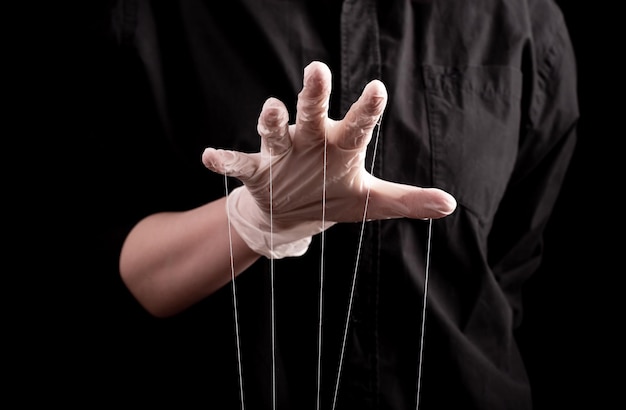 Ręka w rękawiczce medycznej ze sznurkami na palcach Oszustwa w medycynie i farmacji teoria spiskowa oszustwa w opiece zdrowotnej rozpowszechnianie fałszywych informacji o chorobach leki