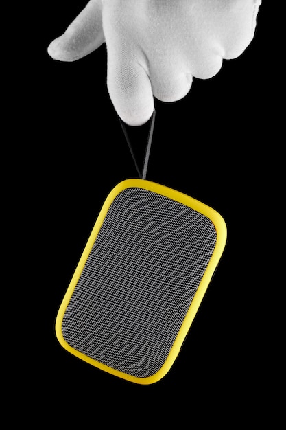 Zdjęcie ręka w rękawiczkach trzyma żółty głośnik bezprzewodowy