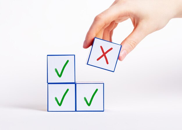 Ręka wybierająca kostkę z krzyżykiem zamiast bloków ze znacznikiem wyboru Negatywna decyzja odrzucenie wybór błędnej odpowiedzi koncepcja