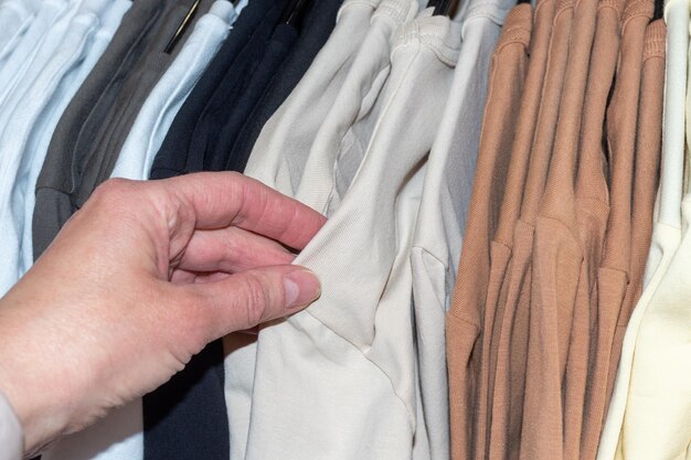 Ręka wybierająca ubrania wiszące na wieszaku w sklepie Koncepcja biznesowa Sprzedaż odzieży