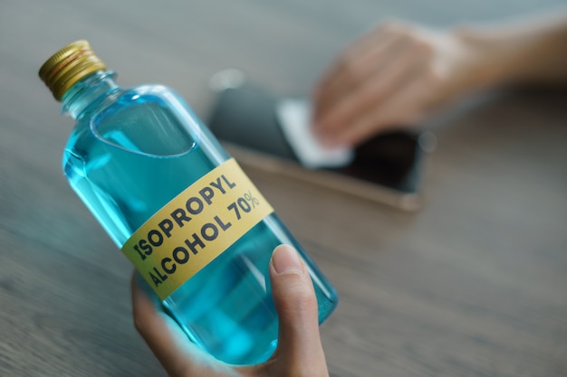 Ręka z alkoholem izopropylowym do czyszczenia telefonu komórkowego