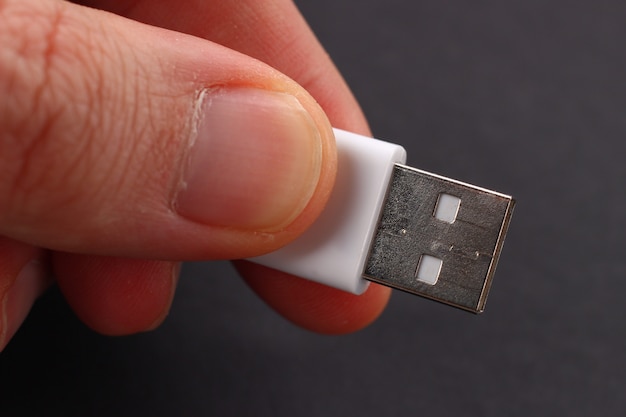 Ręka z białym ładunkiem usb na ciemnym tle