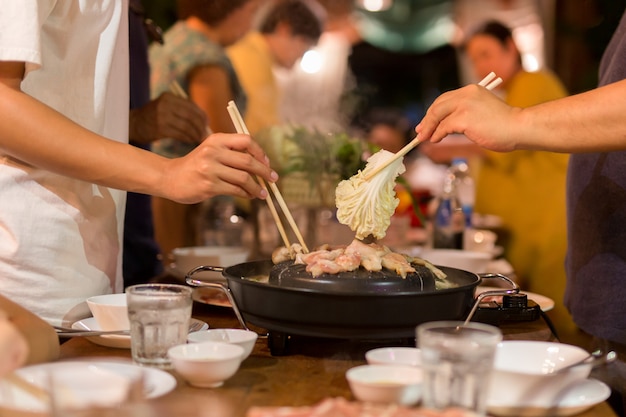 Ręka z chopstick gotowania wieprzowiny bbq i warzyw na rodzinny obiad.