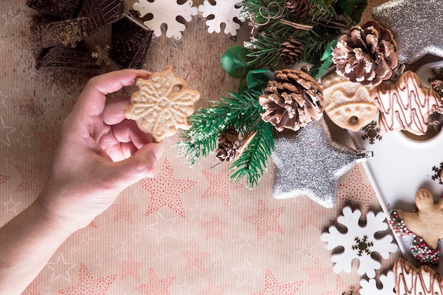 Zdjęcie ręka z ciasteczka świąteczne, jedzenie ciastek, świąteczne dekoracje, na tle gwiazd. świąteczny obiad, dzielenie się z rodziną