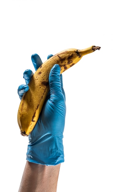 Ręka z niebieską rękawicą lateksową trzymająca banana