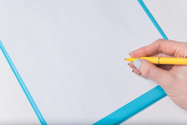 Ręka z piórem na pustym arkuszu papieru. Kobieta składa podpis na papierze. Ścieśniać