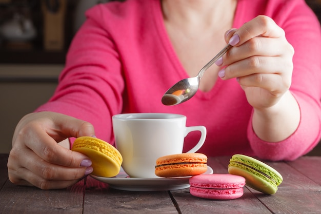 Ręka z smaczne kolorowe macarons na ciemnej powierzchni drewnianych