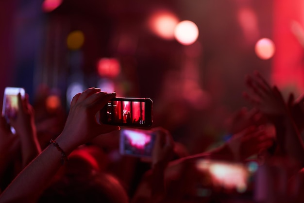 Ręka z telefonem nagrywa festiwal muzyki na żywo Ludzie robiący zdjęcia telefonem podczas koncertu