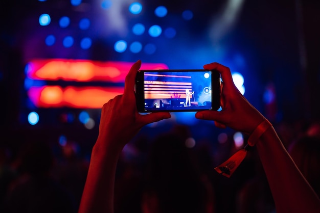 Ręka z telefonem rejestruje festiwal muzyki na żywo Ludzie robiący zdjęcia smartfonem