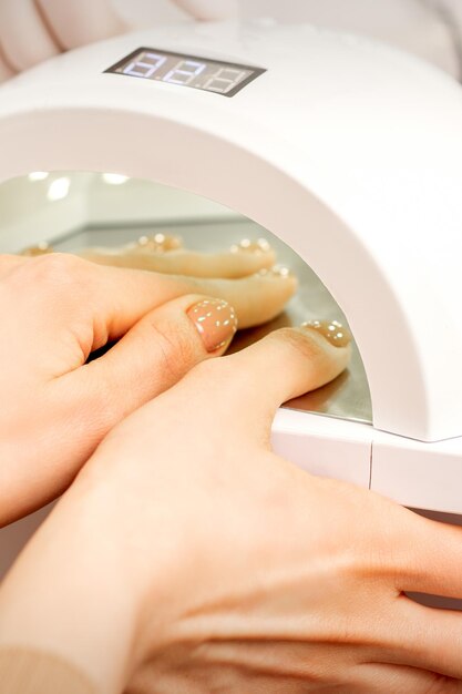 Ręka z wypielęgnowanymi palcami wysuszyć wewnątrz maszyny UV w salonie manicure.