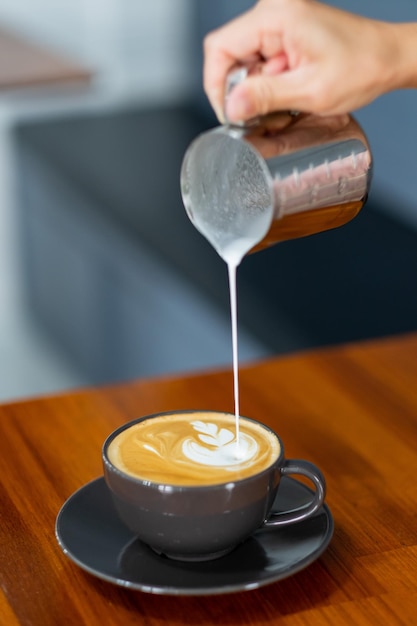 Ręka zbliżenie robi gorącą kawę latte art