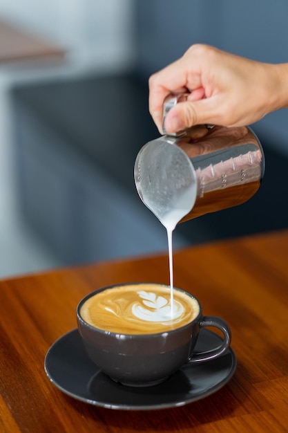 Ręka zbliżenie robi gorącą kawę latte art