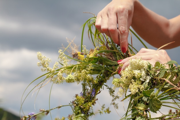 Ręki Wykonuje Wianek Wildflowers Na Błękitnym Chmurnym Niebie Kobieta