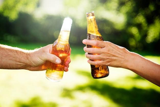 Ręki wznosi toast butelki piwo w parku