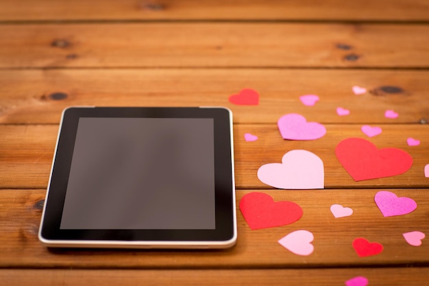 reklama, romans, walentynki i święta koncepcja - zbliżenie komputera typu tablet pc i serca na drewnie