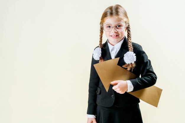 Reklamy i dziecka pojęcie - uśmiechnięta mała dziewczynka wskazuje w lewo z mundurkiem szkolnym z pustą strzała