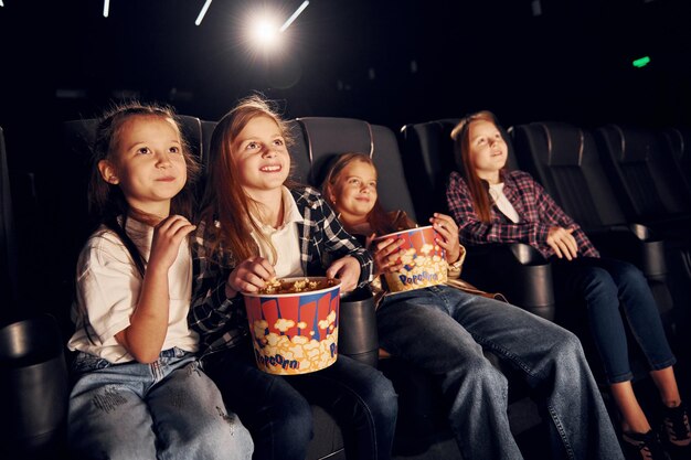 Zdjęcie relaks i dobra zabawa grupa dzieci siedzących w kinie i oglądających razem film