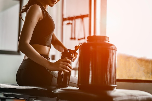 Relaks po treningu. piękna młoda kobieta odwracając wzrok, siedząc na gym.young kobieta na siłowni, robiąc sobie przerwę od treningu. Kobieta warzenia shake proteinowy.