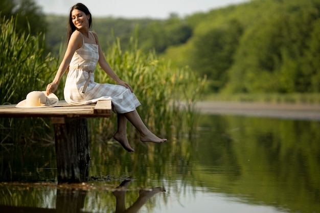 Relaksująca Młoda Kobieta Na Drewnianym Molo Nad Spokojnym Jeziorem