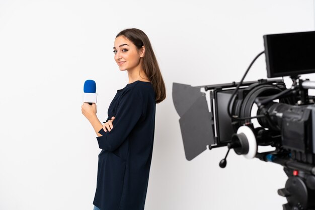 Reporter kobieta trzyma mikrofon i donosi wiadomości na biały w pozycji bocznej