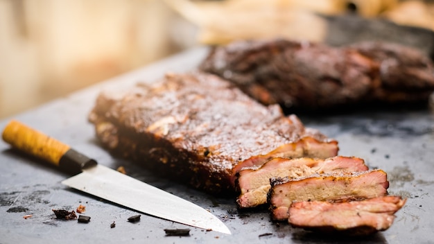 Restauracja Grillowa. Zbliżenie Profesjonalny Nóż I Plasterki Wędzone żeberka Wieprzowe Na Stole W Kuchni.