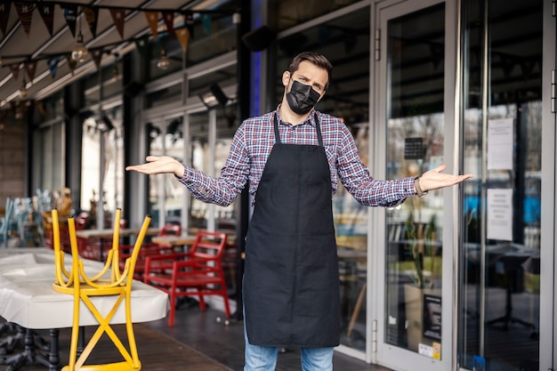 Restauracja zamknięta z powodu COVID-19. Portret kelnera z maską wyrażającą niezadowolenie