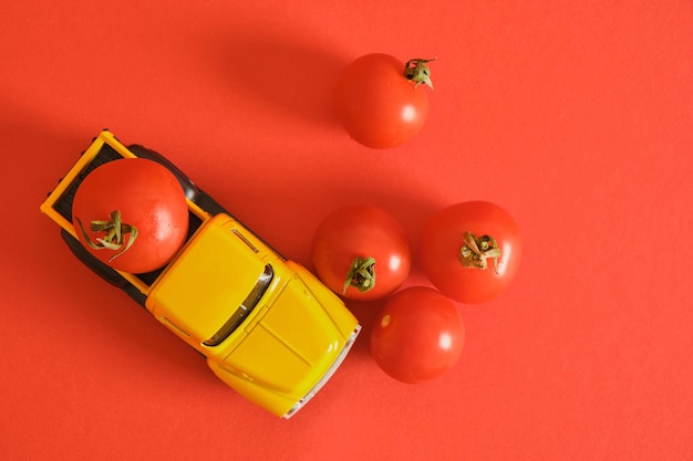 Retro ciężarówka i małe pomidorki koktajlowe na czerwonym tle zbierając reklamę ketchupu