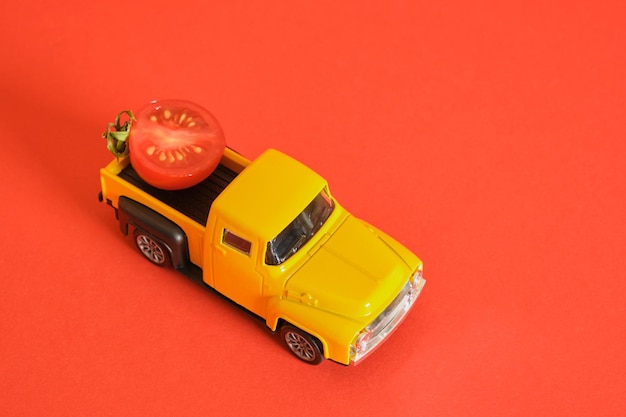 Retro ciężarówka i małe pomidorki koktajlowe na czerwonym tle zbierając reklamę ketchupu