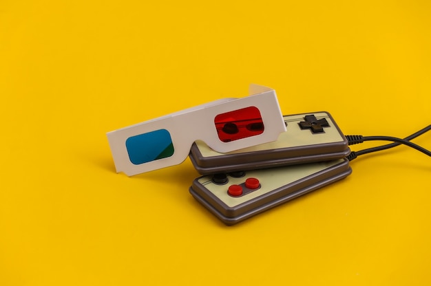 Zdjęcie retro gamepady, okulary 3d na żółtym tle. gry w stylu retro. stereofoniczna gra wideo, lata 80.