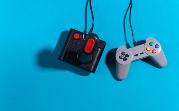 Retro joystick i gamepad na niebieskim tle z cieniem. Gry w stylu retro. Widok z góry