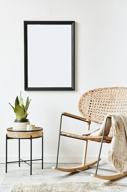 Retro nowoczesna kompozycja wnętrza salonu z designerskim rattanowym fotelem, czarną ramą, stolikiem kawowym, rośliną, dekoracją, białą ścianą i akcesoriami osobistymi.