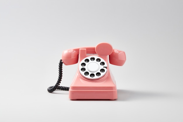 retro różowy obrotowy telefon na białym tle