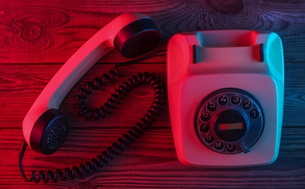 Retro telefon obrotowy na drewnianej powierzchni z czerwono-niebieskim światłem neonowym