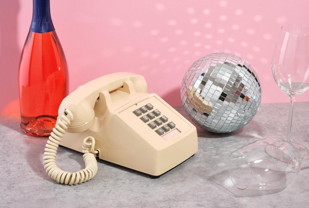 Retro Telefon Z Szarymi Przyciskami Stoi Między Butelką Szampana Błyszczącą Piłką Disko I Okularami