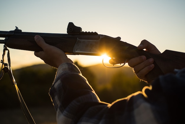 Rifle Hunter sylwetka w pięknym zachodzie słońca. Naboje strzelba. Pociągnął za spust strzelby.