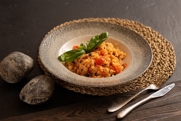 Risotto z boczkiem i pomidorami, ozdobione listkami bazylii, pięknie konserwuje sztućce.