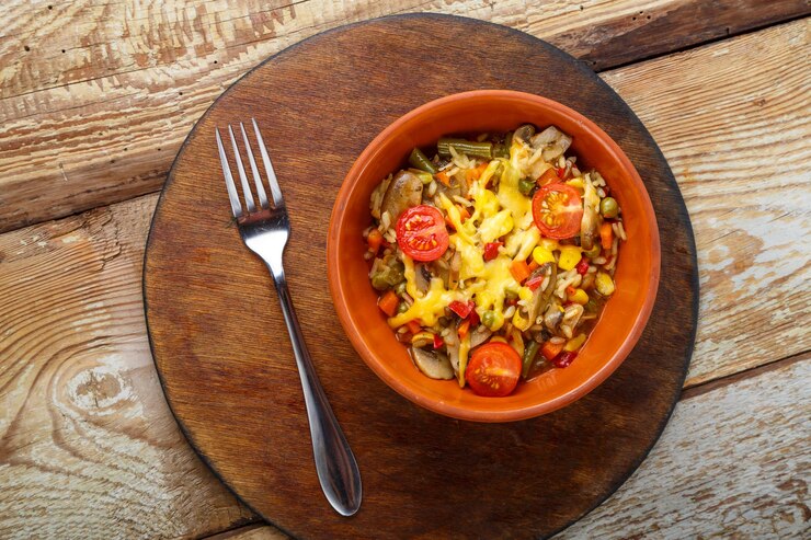 Zdjęcie risotto z grzybami na talerzu na drewnianym tle na drewnianym okrągłym stojaku obok widelca