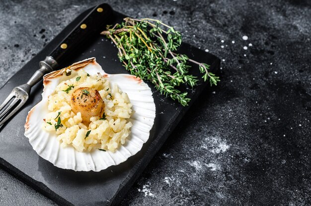 Risotto Z Podsmażanymi Na Patelni Przegrzebkami Morskimi W Skorupce. Czarne Tło. Widok Z Góry. Skopiuj Miejsce.