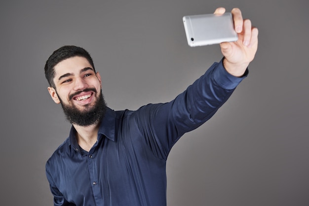 Robi selfie szczęśliwy uśmiechający się przystojny brodaty młody człowiek